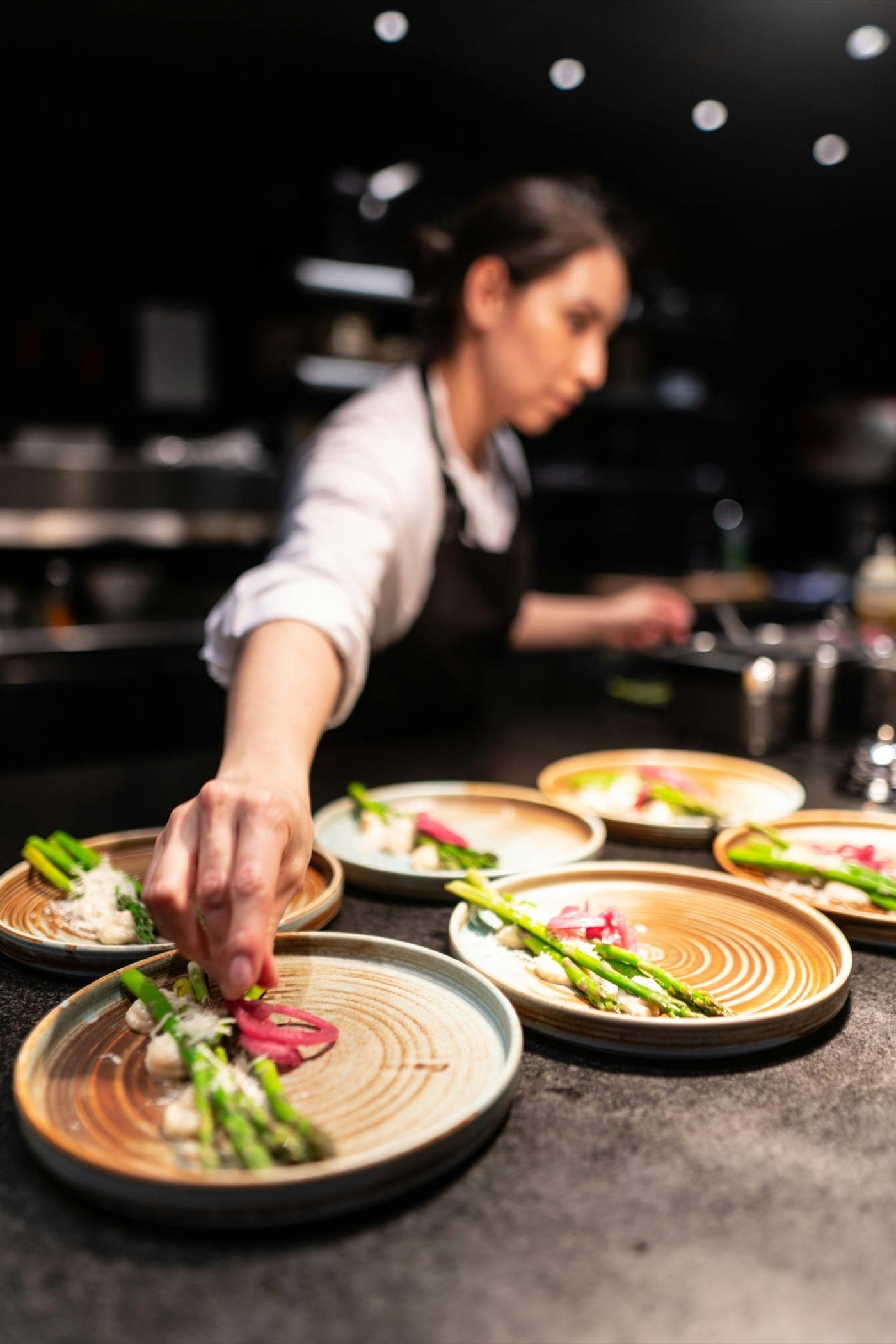A chef plating several dishes on the line during service